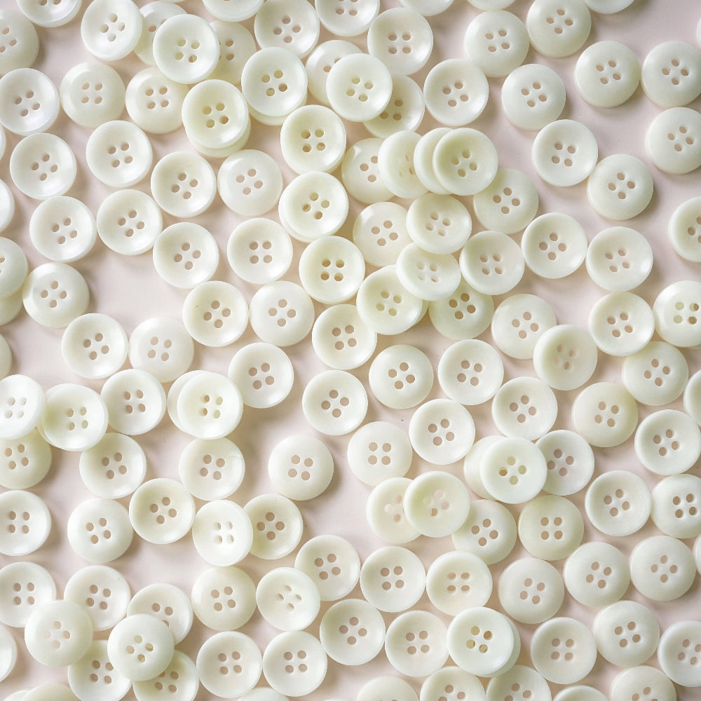 Close-up of a large number of white buttons on a light pink background