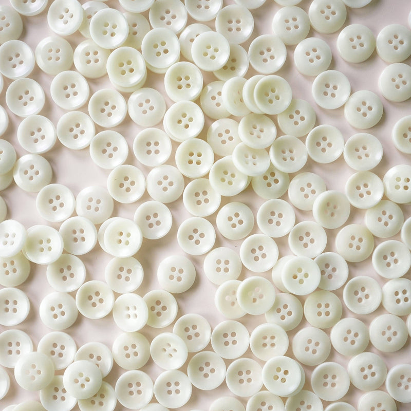 Close-up of a large number of white buttons on a light pink background