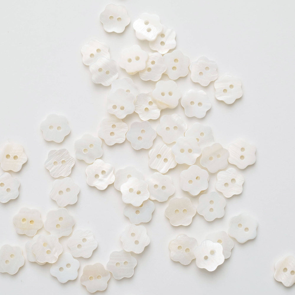 White floral buttons scattered on a light gray background