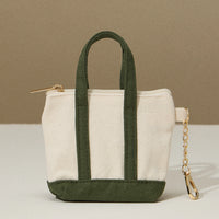 Small tote bag with green handles and base on a beige background