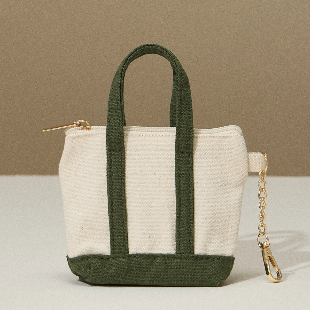 Small tote bag with green handles and base on a beige background