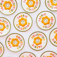 Multiple iron on patches with a yellow flower with the words "Fabric Collector" in colorful letters against a white background. 