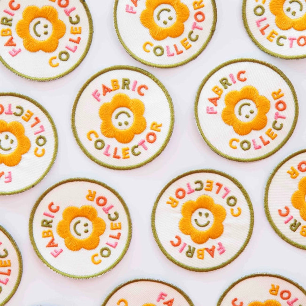Multiple iron on patches with a yellow flower with the words "Fabric Collector" in colorful letters against a white background. 