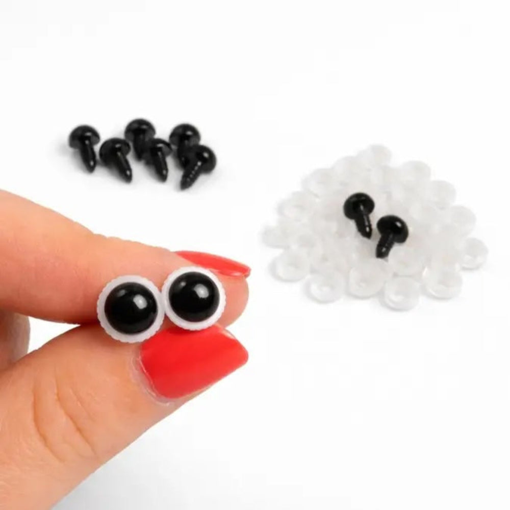 Small black and white eyes held between fingers with additional eyes on a white background