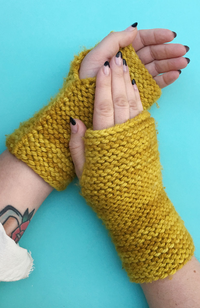 Dark yellow knit fingerless mittens worn on manicured hands on a bright blue background.