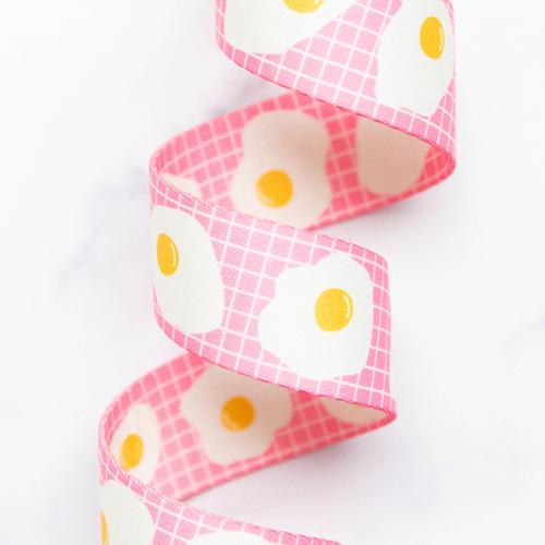 Pink webbing with fried egg pattern on a white background