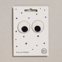 Pair of round eye iron-on patches with black centers on a white card with star patterns, branded 'Petit Bateau'.
