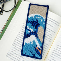 Needlepoint bookmark with a wave design on an open book with glasses on a white background