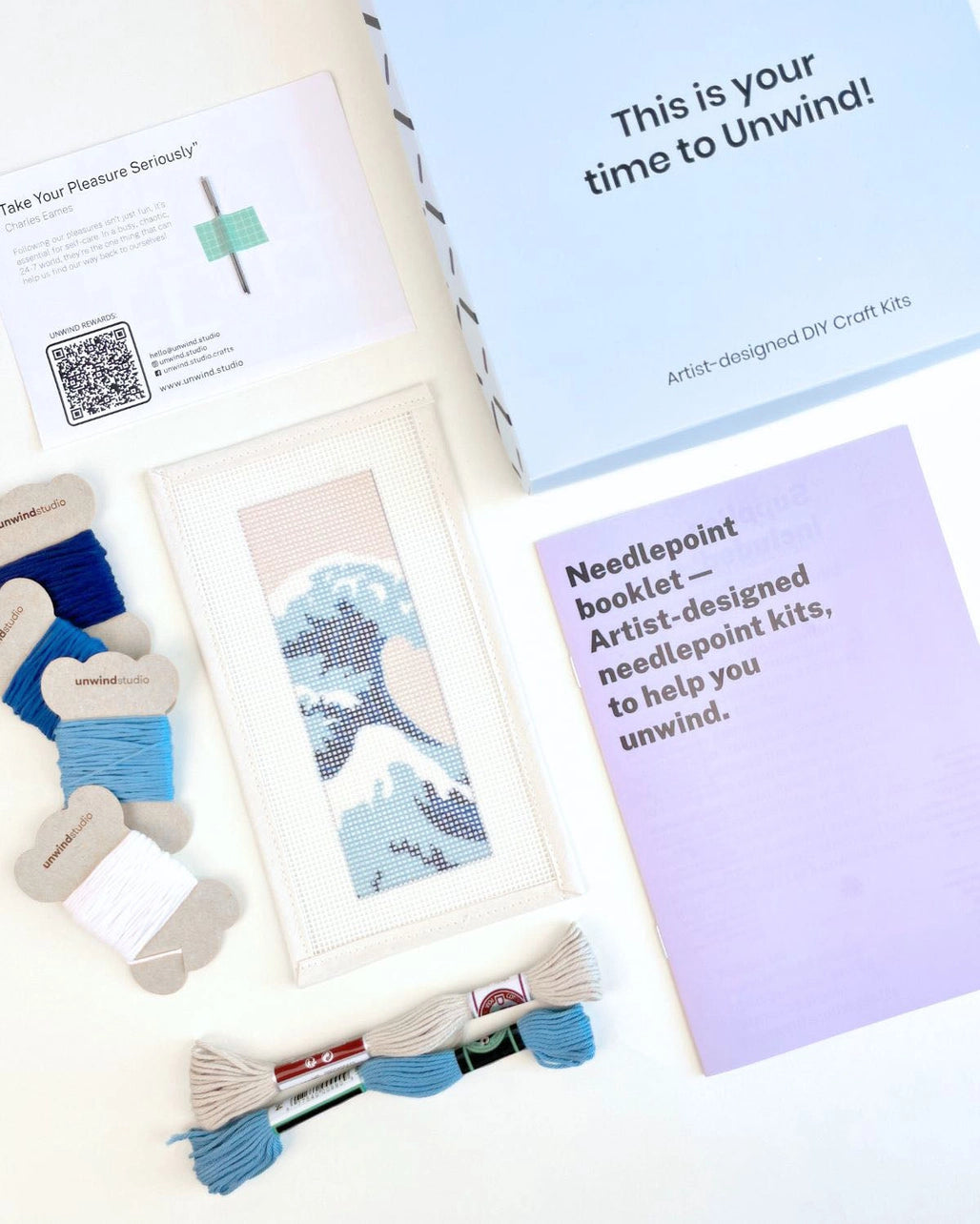 Needlepoint kit materials including canvas, thread, and instructions on a white background