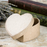Heart-shaped cardboard box on a textured surface with books and lavender in the background