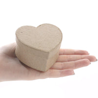 Heart-shaped wooden box held in a hand on a white background