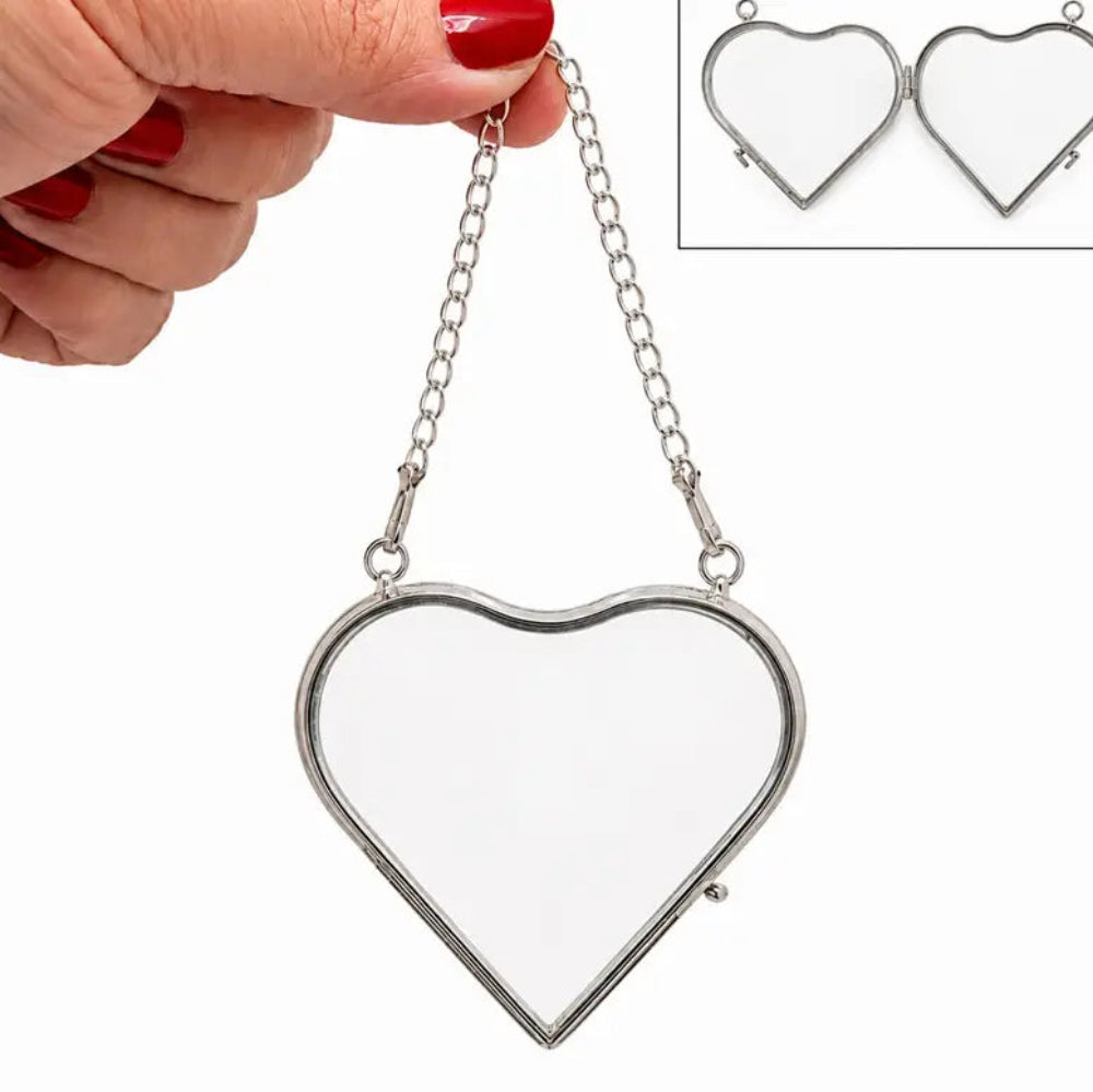 A heart-shaped metal frame with a clear glass insert, held by a hand with red nail polish. An inset in the top right shows the heart pendant open