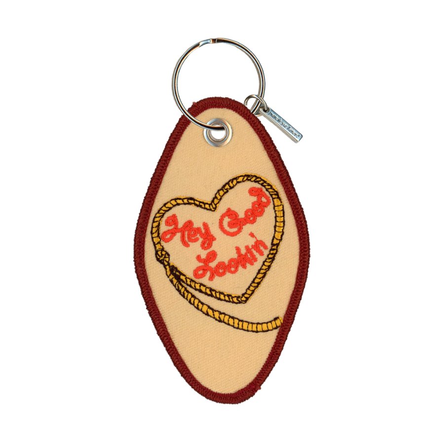 Tan embroidered motel-style keychain that reads "hey good lookin" inside a heart-shaped rope