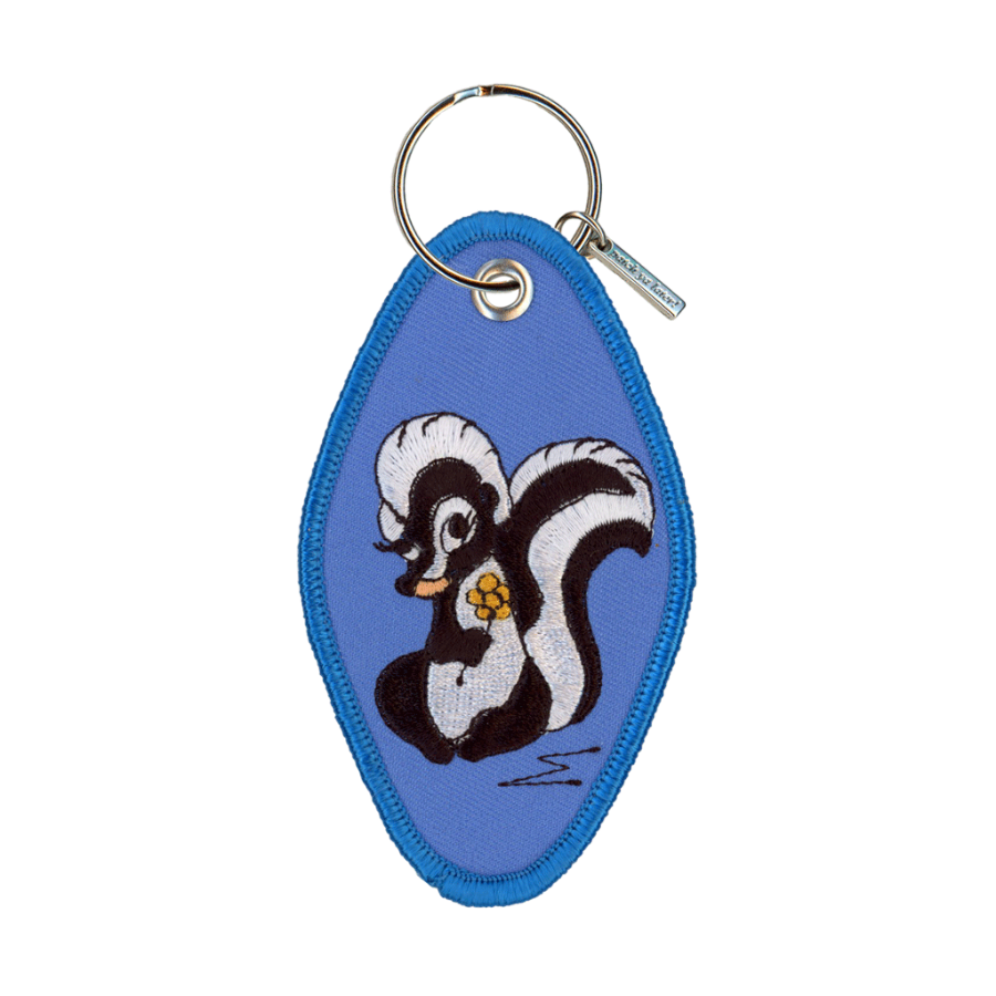 Blue embroidered motel-style keychain featuring a skunk design