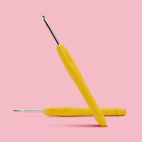 yellow crochet hook on a pink background