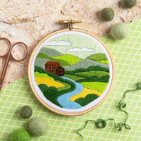 Embroidery hoop with a landscape design on a green grid background