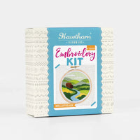 Embroidery kit packaging with scenic design on a white background