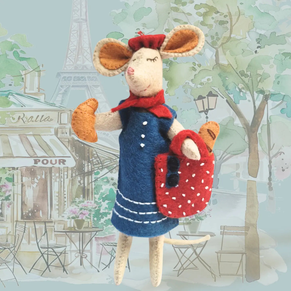Handmade felt mouse toy in a Parisian setting with Eiffel Tower in the background.