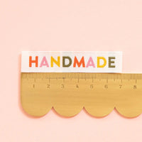 Wood ruler with 'HANDMADE' text on a pink background