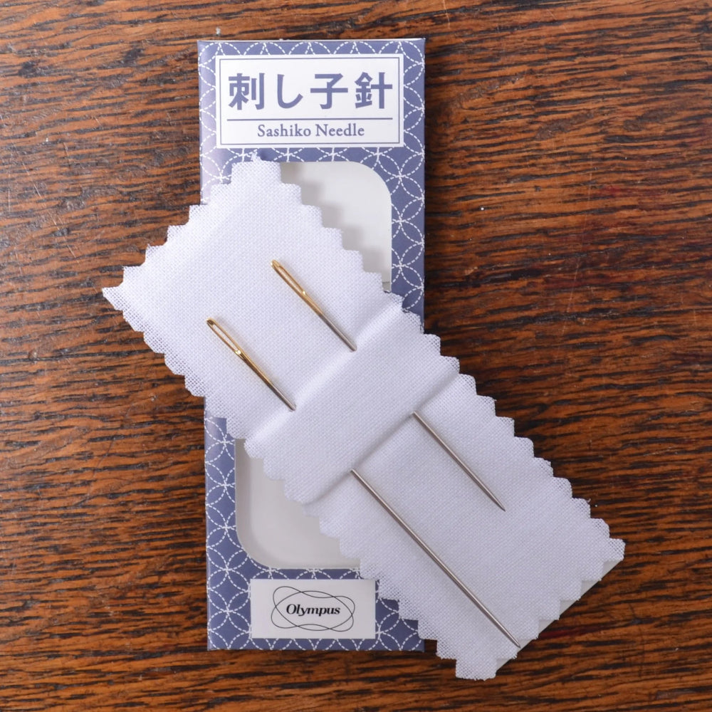 Sashiko needles in a packaging on a wooden surface