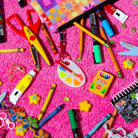 Paint Palette Bag Charm attached to a pouch with different crafting tools spread around it like pencils, markers, scissors, crayolas...