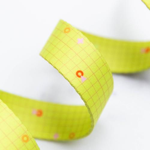Close-up of a roll of yellow webbing with small decorative elements on a white background