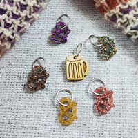 Collection of colorful pretzel stitch markers on a textured fabric background
