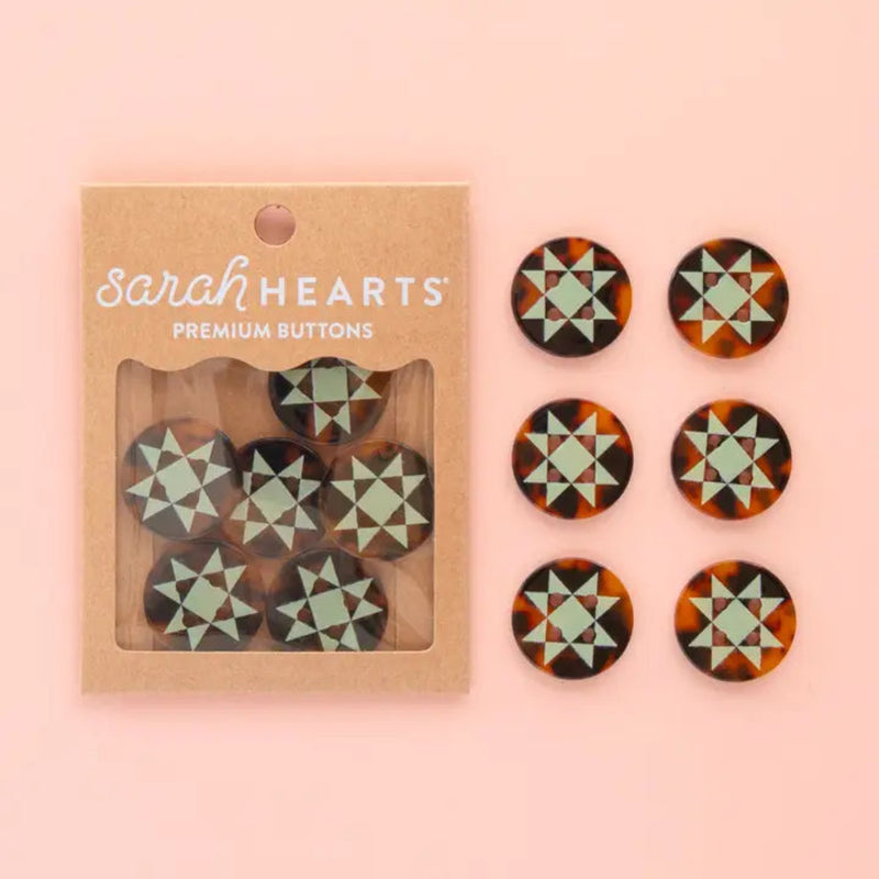 Six tortoise shell buttons with mint green geometric star patterns in packaging that says "Sarah Hearts Premium Buttons" on a pink background. Six buttons are placed int two rows next to the package. 