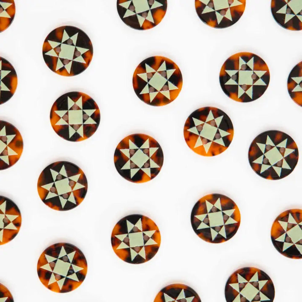 Tortoise shell buttons with mint green geometric star patterns on a white background.