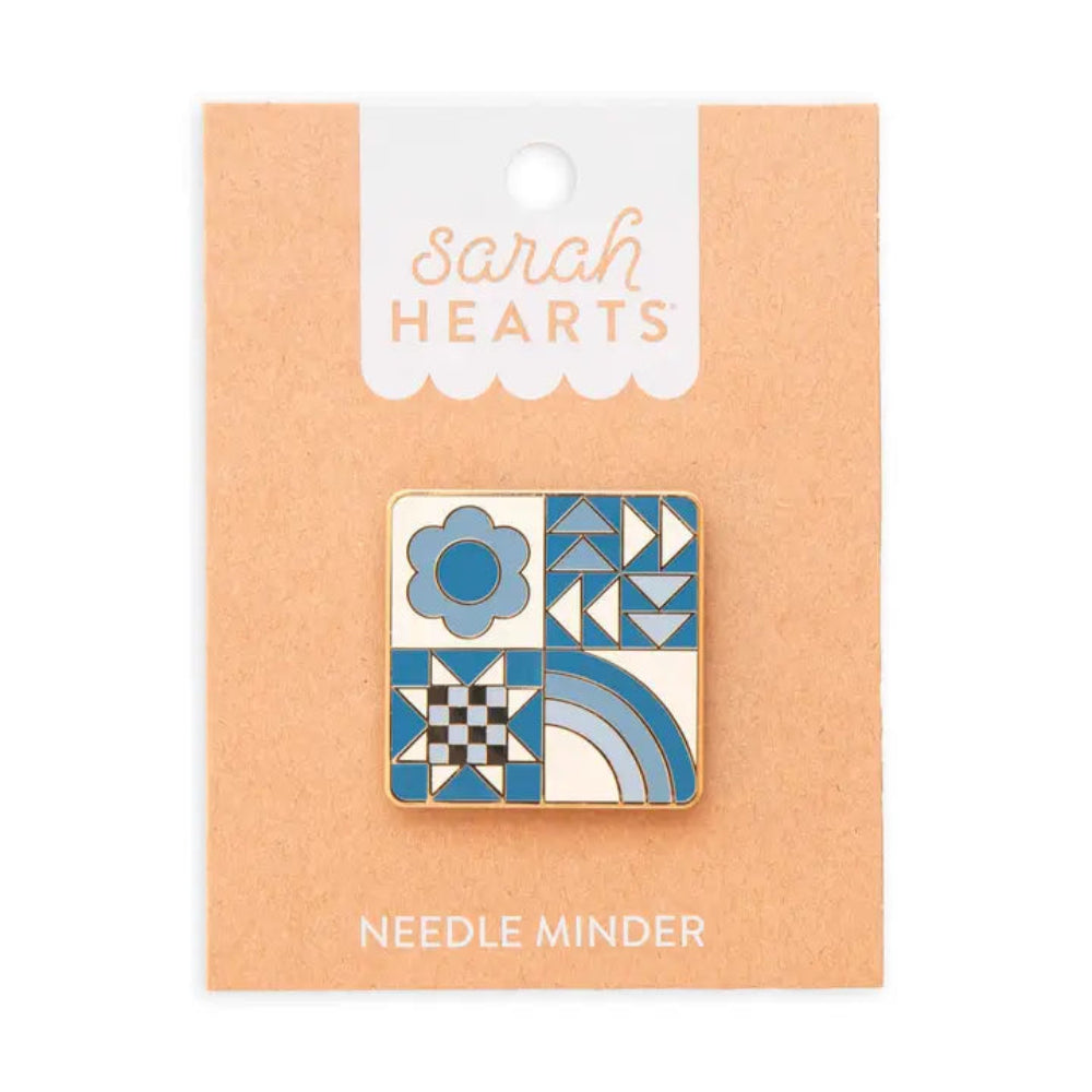 Square needle minder with different designs: blue flower, a quilting star, triangles, and a rainbow on brown backing labeled "Sarah Hearts"