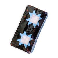 A tortoise hair clip adorned with two blue quilt star shapes, against a white  background. 