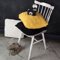 Yellow cushion with a camera on a white chair against a dark background