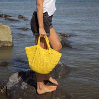 Woman holding a yellow bag by the water