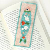 Needlepoint bookmark with a colorful fish design against an open book background