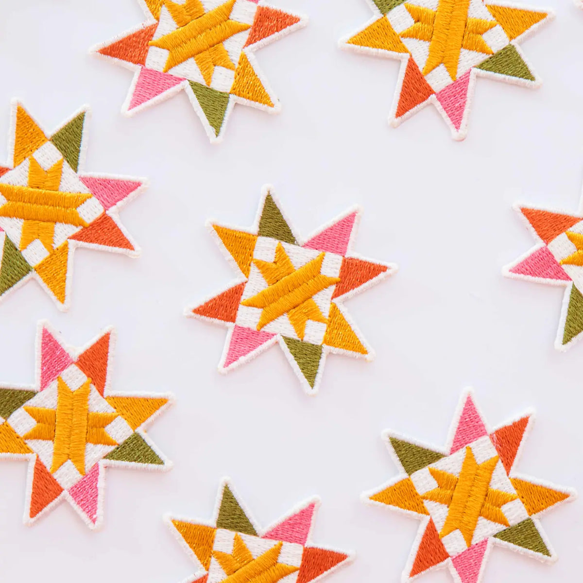Colorful iron-on patches in the shape of a sawtooth quilt block on a white background