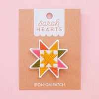 Colorful sawtooth quilt block iron-on patch on a 'Sarah Hearts' branded card with a pink background