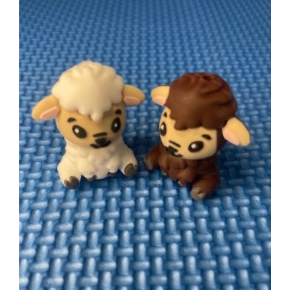 Two small sheep point protectors, one white and one brown, on a blue textured background.