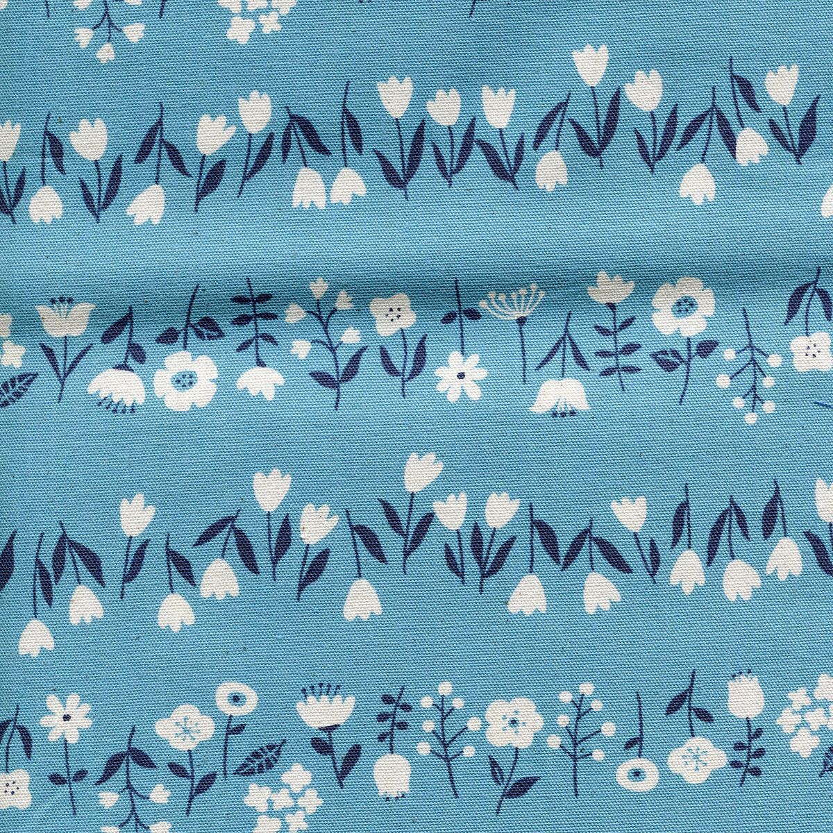 Patterned fabric featuring white flowers with dark blue stems and leaves on a light blue background