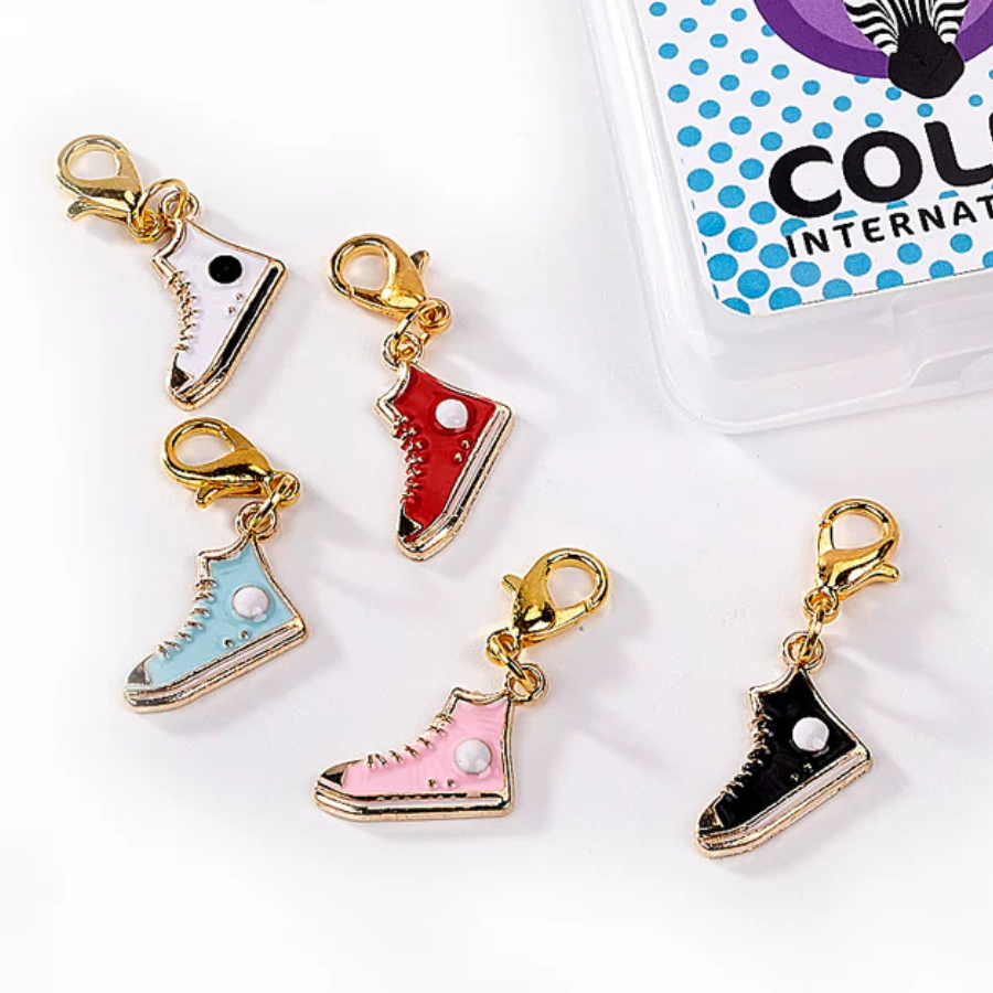 Enamel and metal sneaker-shaped stitch markers in assorted colors, with gold metal lobster clasps.