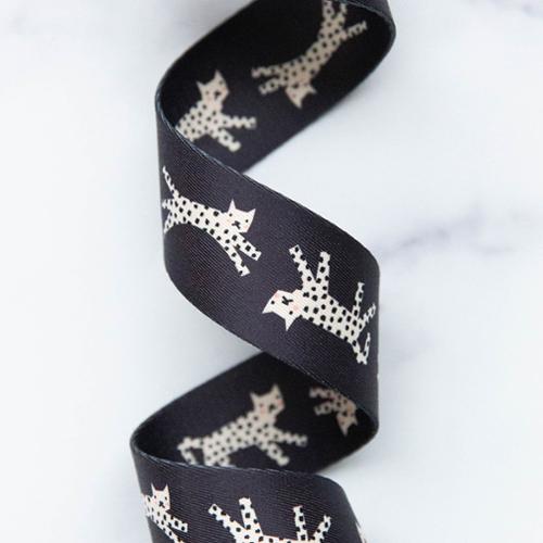Close-up of black webbing with images of snow leopards on it against a white background.