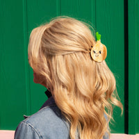 Person with blonde hair wearing an onion hair clip against a green background