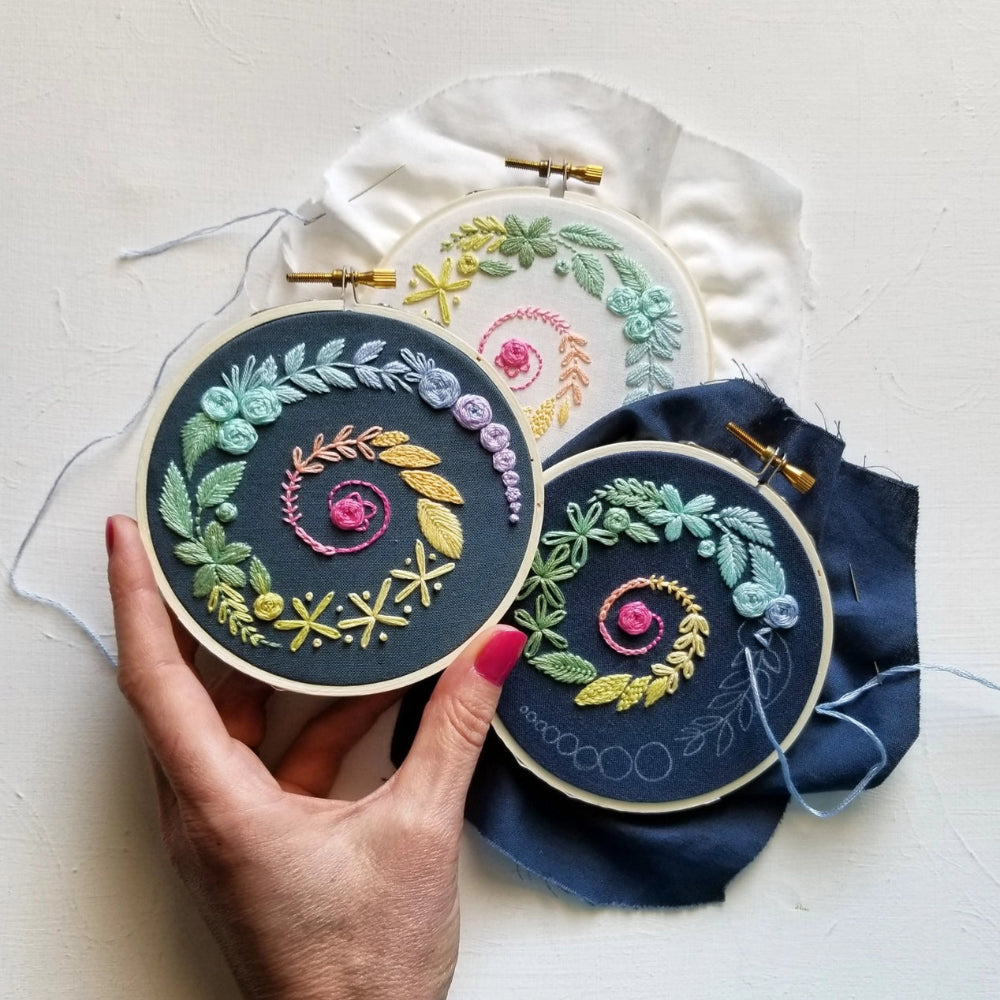Three embroidery hoops with a spiral floral design in many colors