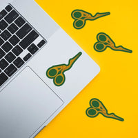 A sticker with an illustration of stork scissors with a green background on a laptop and on a yellow background. 