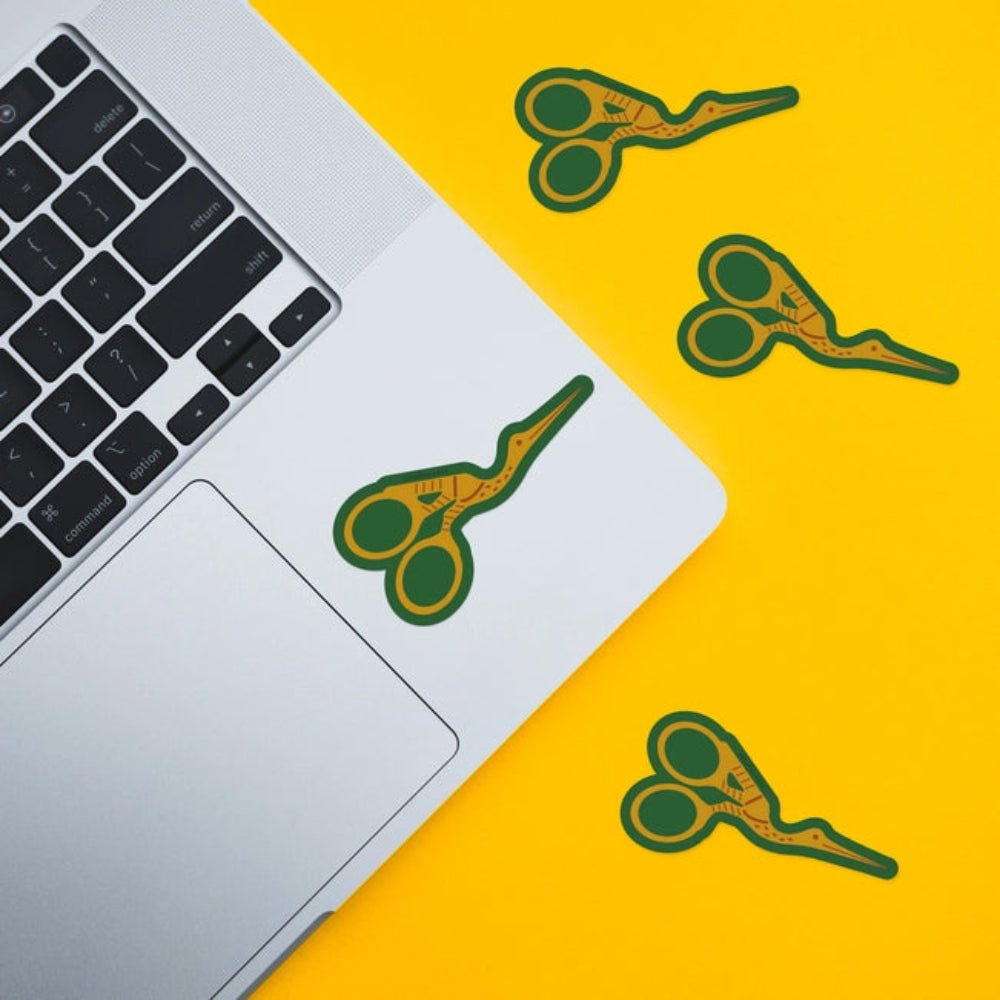 A sticker with an illustration of stork scissors with a green background on a laptop and on a yellow background. 