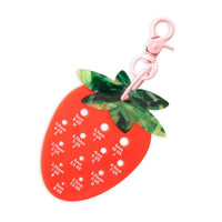 A strawberry-shaped tool for measuring hook sizes with labeled holes in white text against a white background