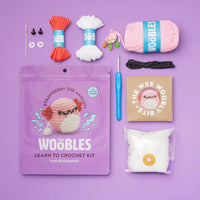 Crochet kit with yarn, hooks, and packaging on a purple background