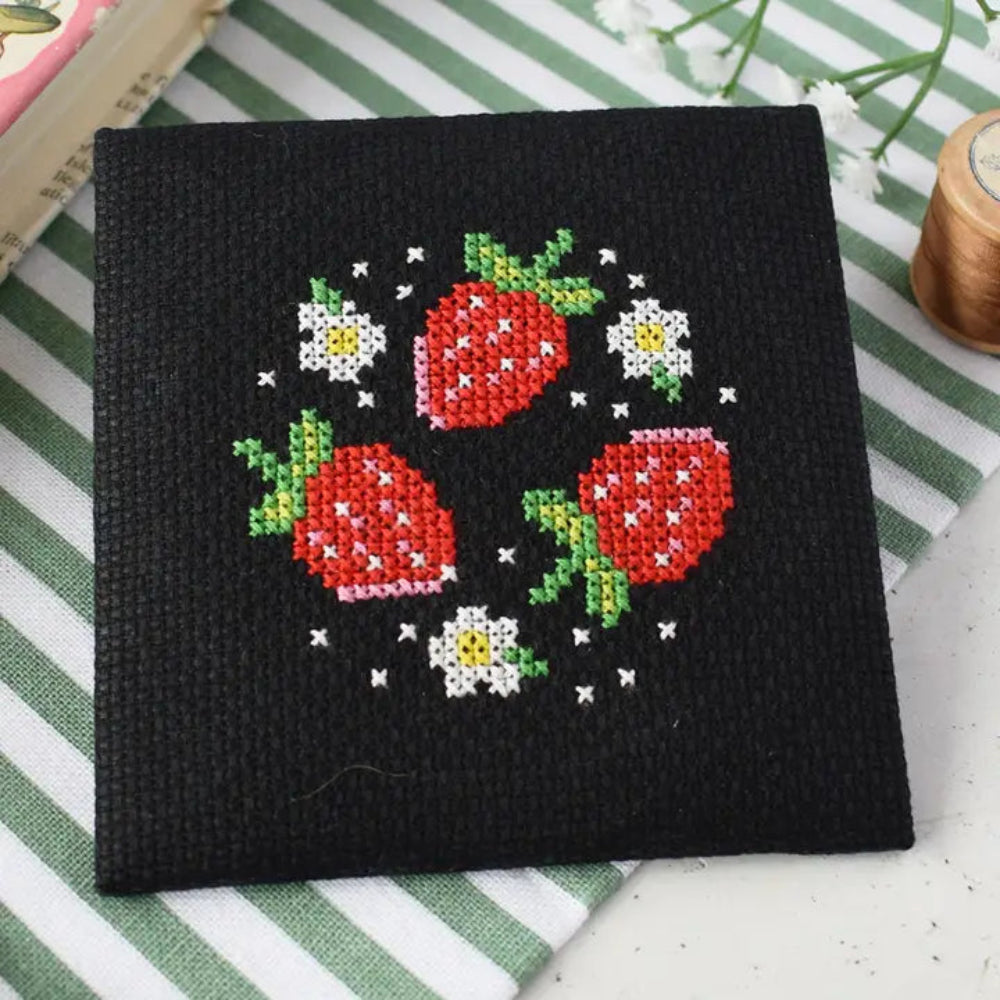 Cross-stitched strawberries and flowers on a black fabric background
