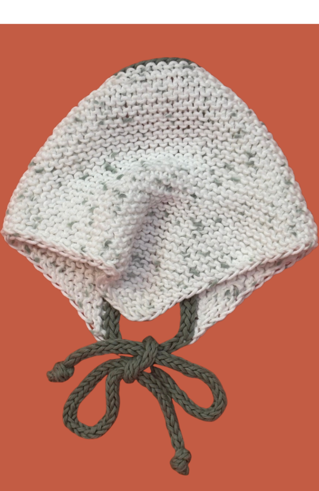 Knitted white bandana with green ties on an orange background.