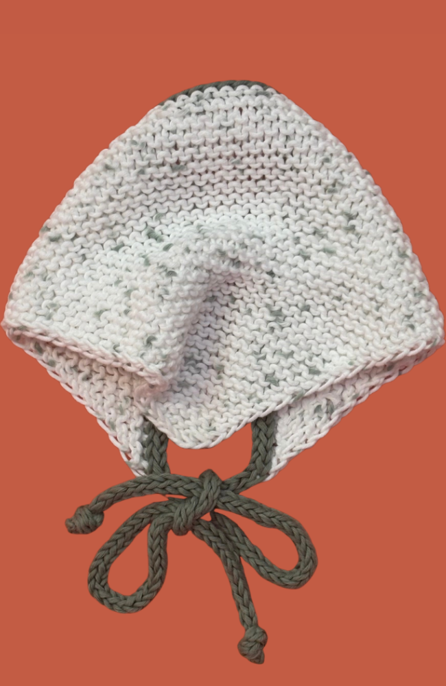 Knitted white bandana with green ties on an orange background.
