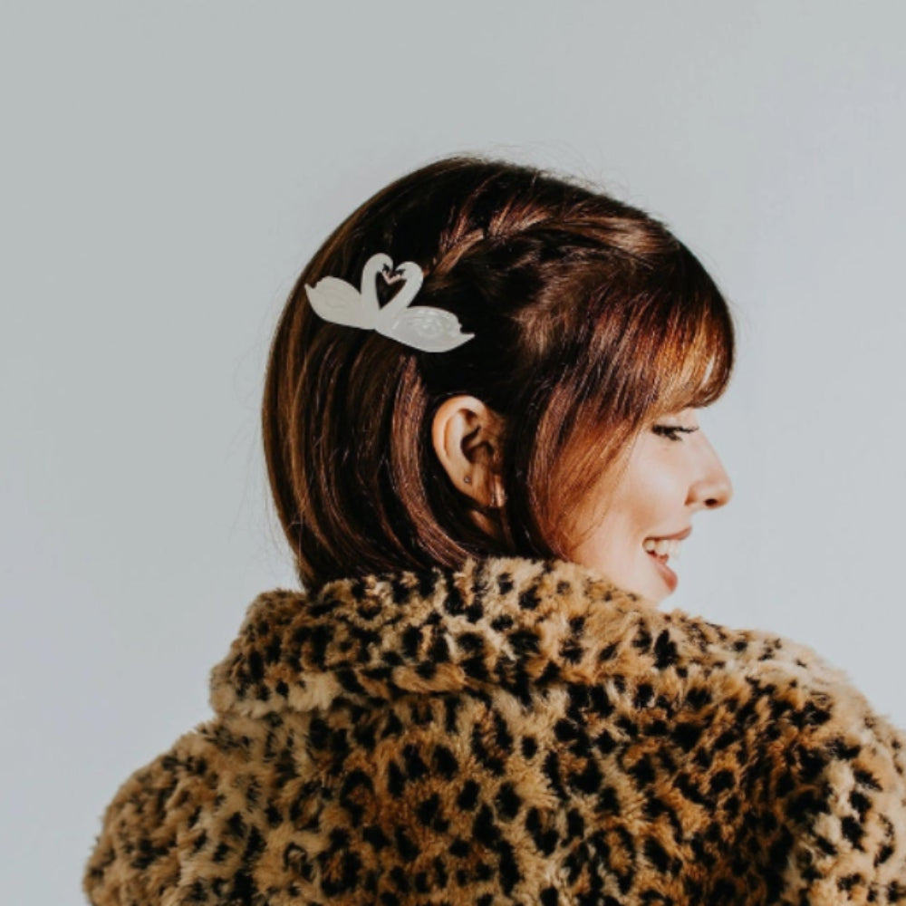 Person wearing a leopard print coat with a neutral background and a swan clip in hair.